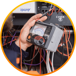 An electrical technician carefully using an electronic multimeter to measure voltage in a circuit.