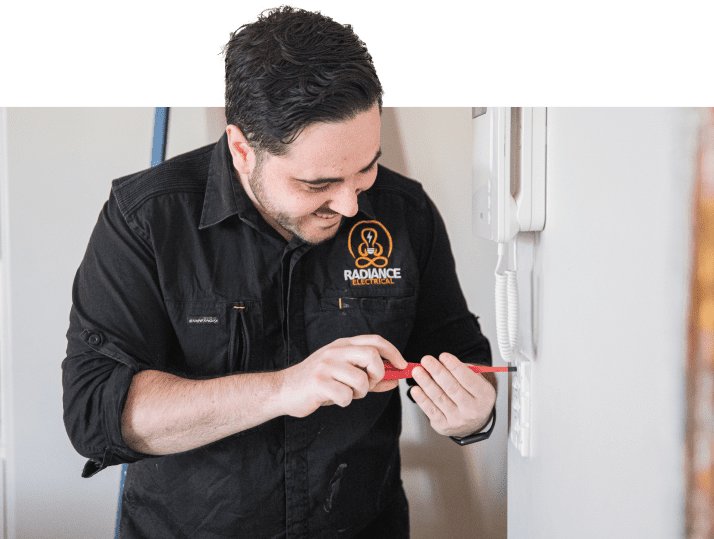 A man in a black shirt is repairing a light switch.